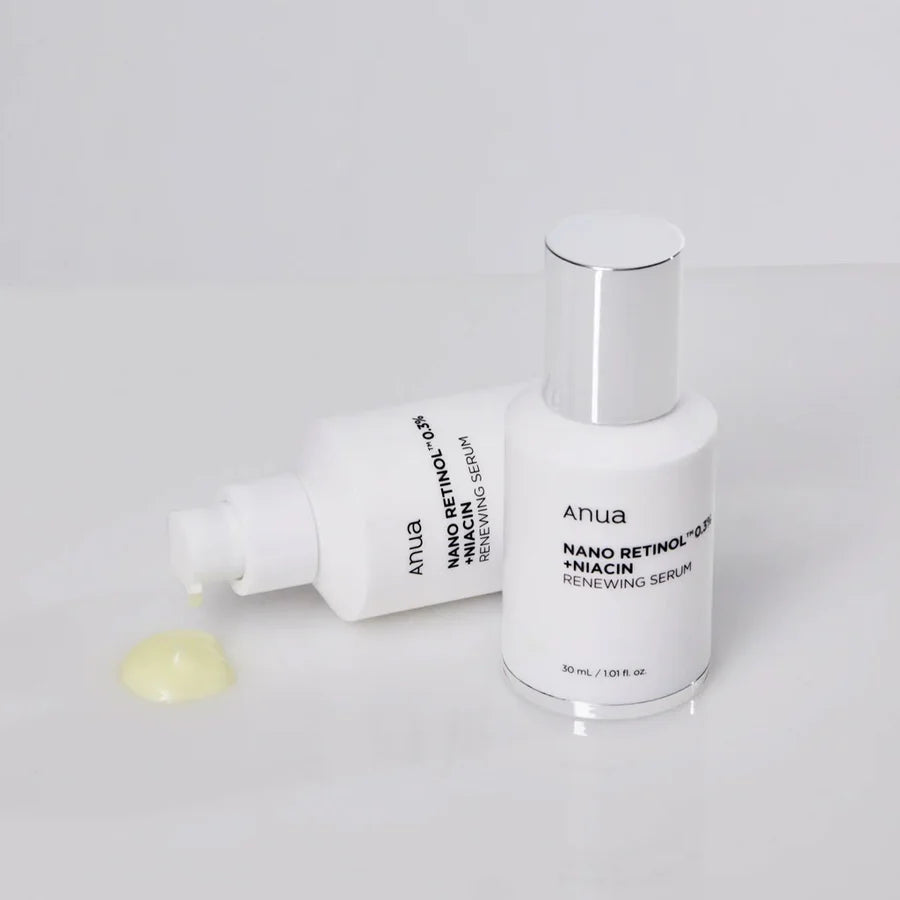 Anua niacinamide and retinol night treatment serum bottles with dropper and serum drop on white surface