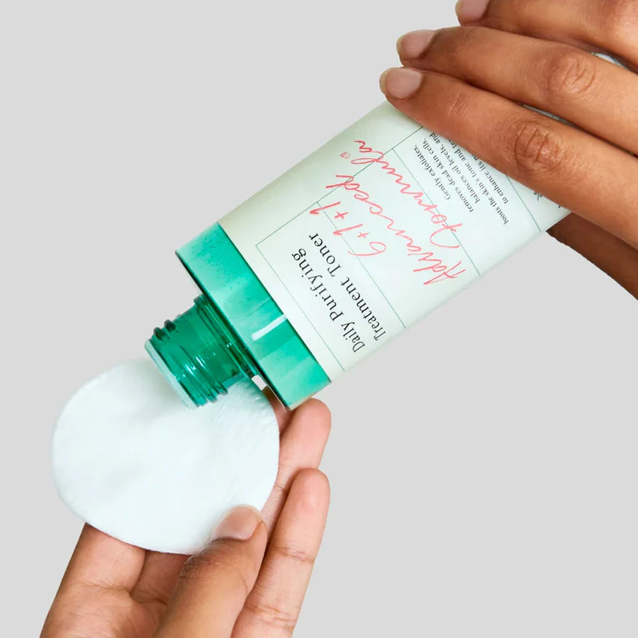 AXIS-Y daily purifying toner being poured onto a cotton pad from a green-capped bottle