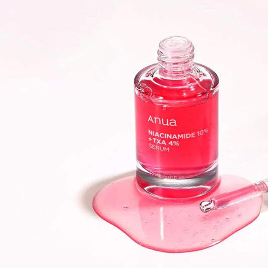 Anua brightening serum with TXA and niacinamide in a clear glass bottle with pink liquid and dropper