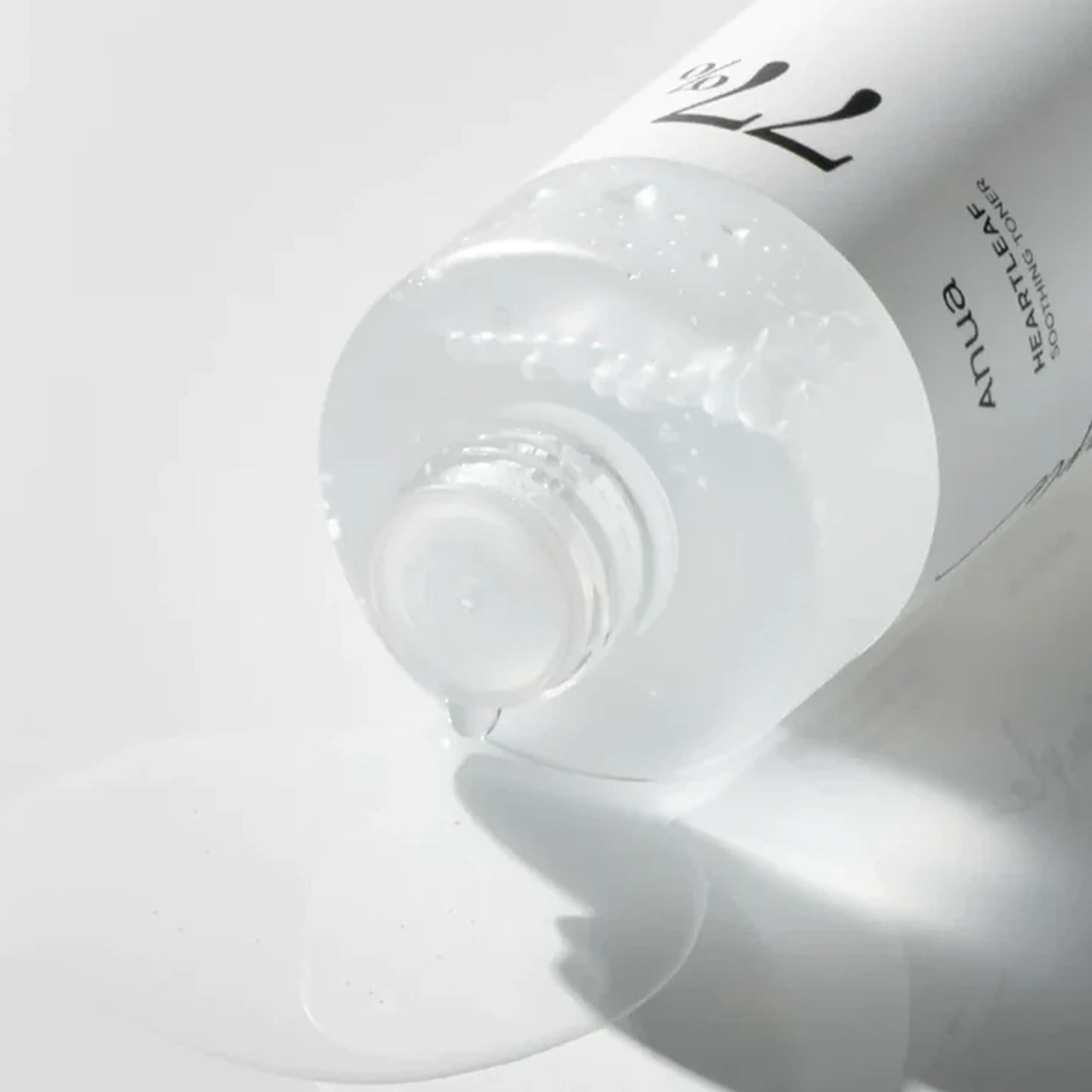 Anua Heartleaf 77 Soothing Toner mini bottle pouring clear toner liquid on white surface