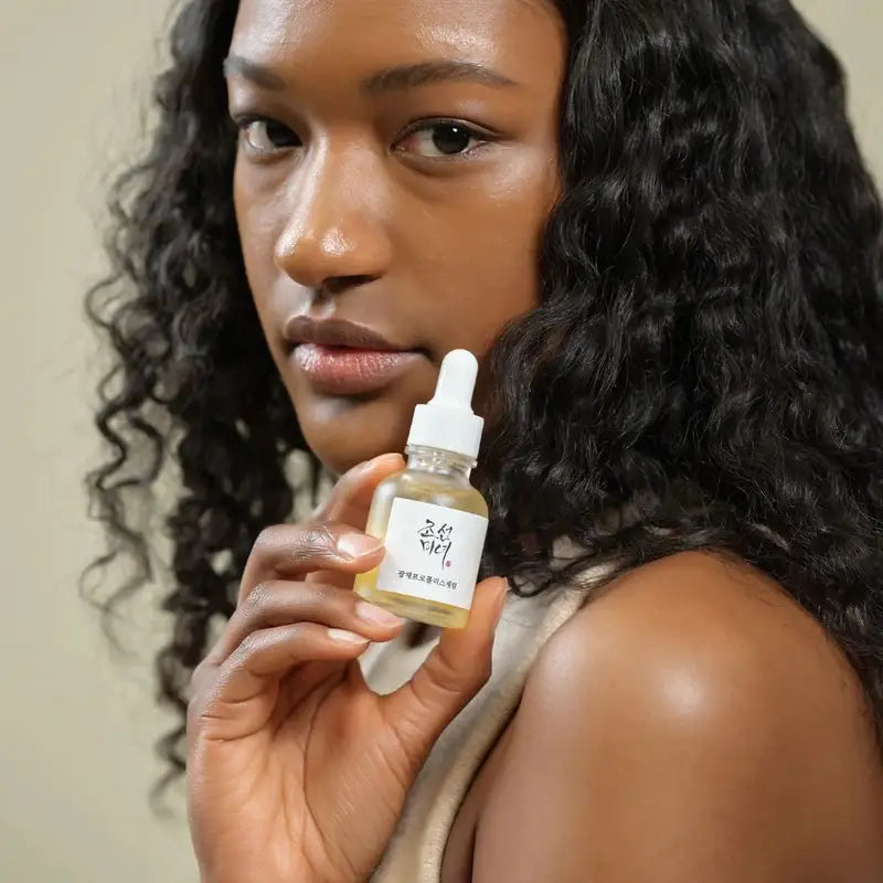 Beauty Of Joseon Propolis Niacinamide Serum held by a model with curly hair for glowing skin