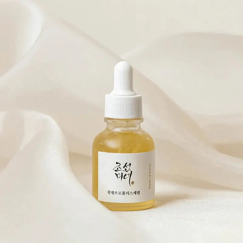 Beauty Of Joseon Propolis Niacinamide Serum in a clear bottle on a soft fabric backdrop